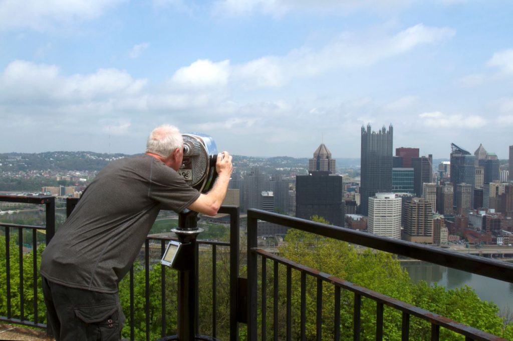 Picture of a man looking through a viewfinder at downtown Pittsburgh