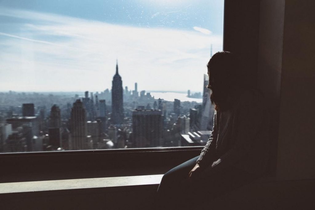 Silhouette of a person observing a city skyline through a window, representing intelligence analysis, observation, and perspective.